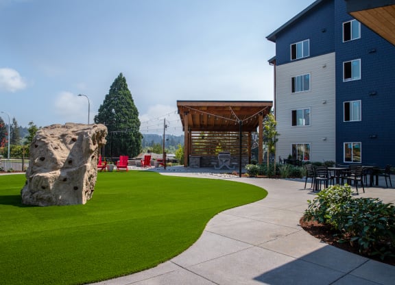 a large rock sits in the middle of a grassy area with a building in the backgroundat Scouter's Mountain, Happy Valley, OR