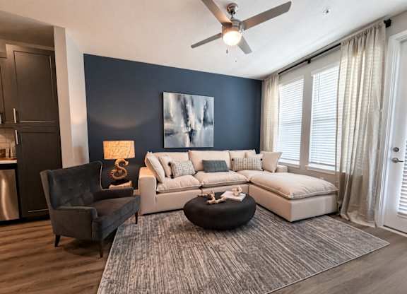 A modern living room with a grey rug, a black chair, a white sofa, and a painting on the wall.