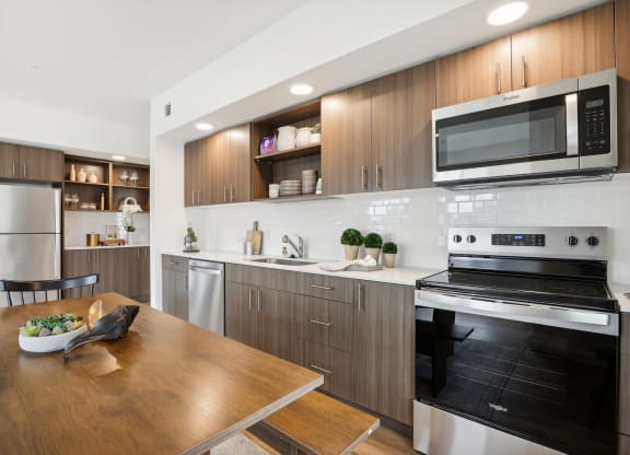 a kitchen with stainless steel appliances and a wooden table at The Mill on Maple Apartments, Oregon City