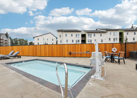 our apartments have a pool and a patio with chairs and tables at The Mill on Maple Apartments, Oregon City, OR