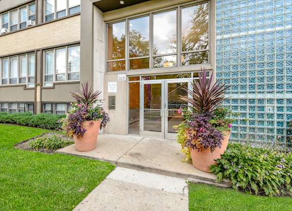 A building with a glass door and windows with plants in front. at Academy at Drexel Apartments, Illinois