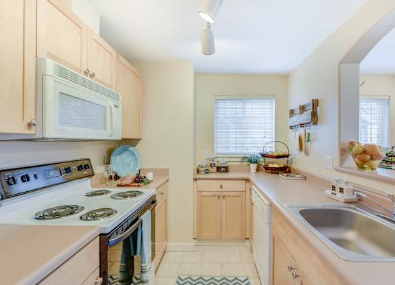 A kitchen with a stove, sink, and microwave at The Lodge at Peasley Canyon in Federal Way, Washington 98001