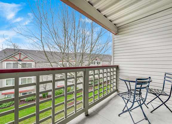 A balcony with a table and chairs overlooking a building at The Lodge at Peasley Canyon in Federal Way, WA
