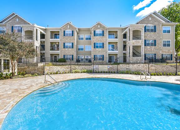 A large apartment complex with a swimming pool in front.