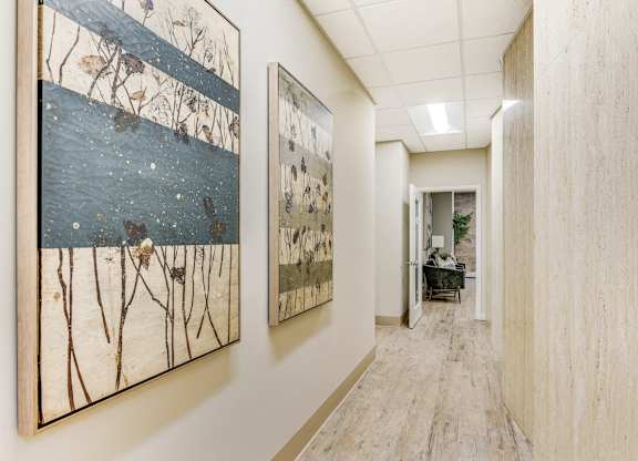 A hallway with two paintings on the wall and a doorway at the end. at Academy at Drexel Apartments, Chicago, IL, 60637