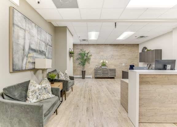 A spacious office lobby with a grey couch, wooden floors, and a reception desk. at Academy at Drexel Apartments, Chicago, Illinois