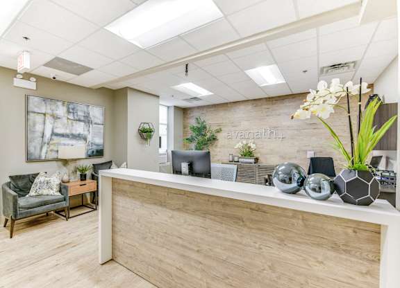 A reception area with a wooden desk and a couch. at Academy at Drexel Apartments, Chicago