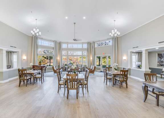 A large dining room with wooden chairs and tables at Manor at Victoria Park, Temple Hills, MD