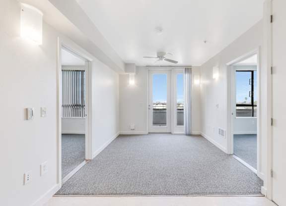 A spacious, empty room with a ceiling fan and carpeted floor. at Acton Courtyard, Berkeley