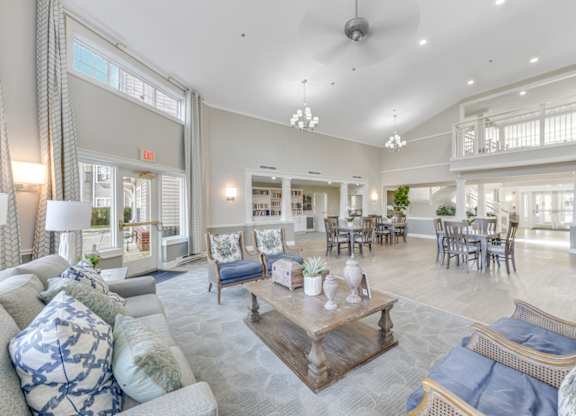 A spacious community lounge room with a variety of seating options and a large window at Manor at Victoria Park, Temple Hills, Maryland