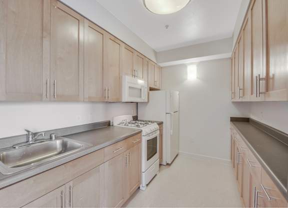 A kitchen with wooden cabinets and a white refrigerator. at Acton Courtyard, Berkeley, CA, 94703