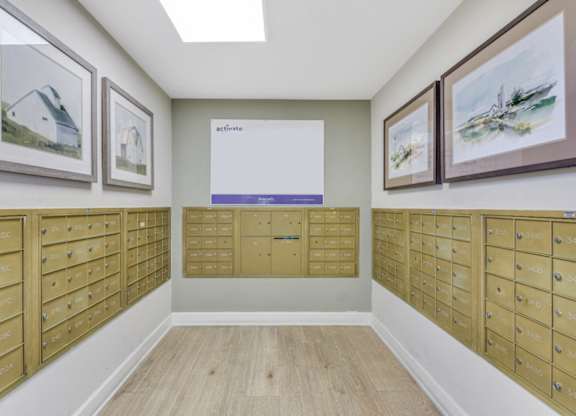 A room with a wall of mailboxes and pictures on the wall at Manor at Victoria Park, Temple Hills, MD 20748
