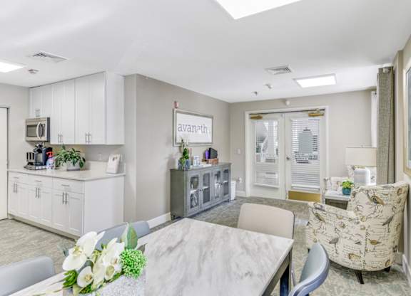 A well-lit, modern resident kitchen with a breakfast bar and a dining table set with a vase of flowers at Manor at Victoria Park, Temple Hills, MD