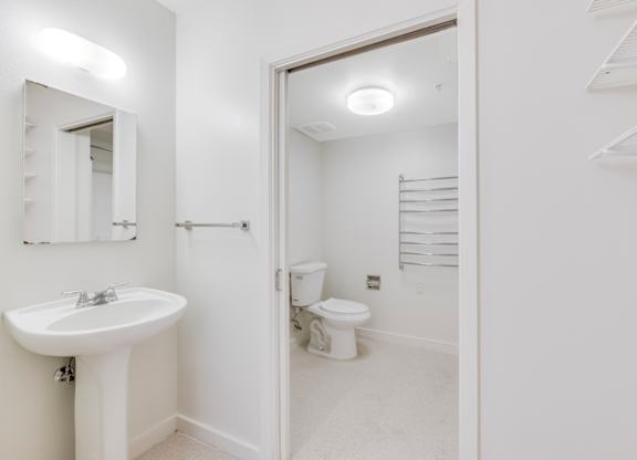 A white bathroom with a sink, toilet, and mirror. at Acton Courtyard, Berkeley, 94703