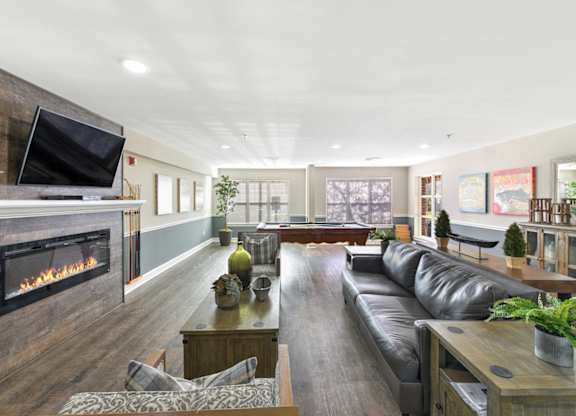 A modern living room with a fireplace and a long black leather sofa at Manor at Victoria Park, Temple Hills, MD 20748