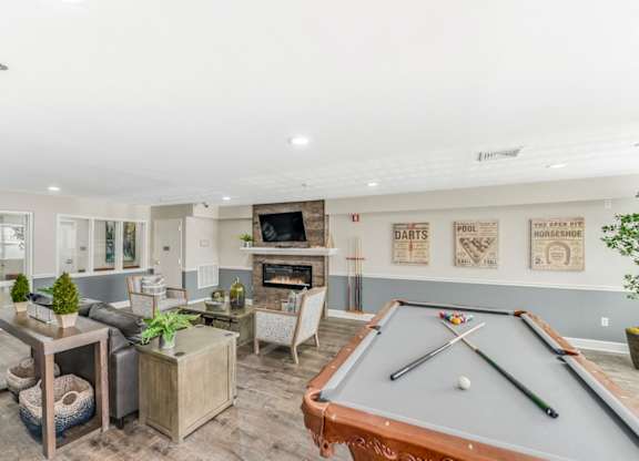 A billiard table is in the middle of a room with a fireplace and a TV at Manor at Victoria Park, Temple Hills, MD