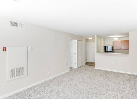A spacious, empty room with a fire extinguisher on the wall at Manor at Victoria Park, Temple Hills, MD