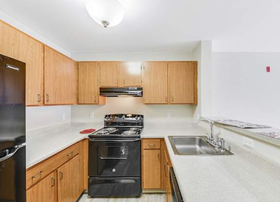A kitchen with wooden cabinets and a black stove top oven at Manor at Victoria Park, Temple Hills