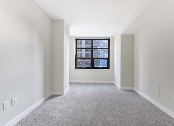 A room with a carpeted floor and a window with a view of a building. at Affinity at 2M, Washington, 20002