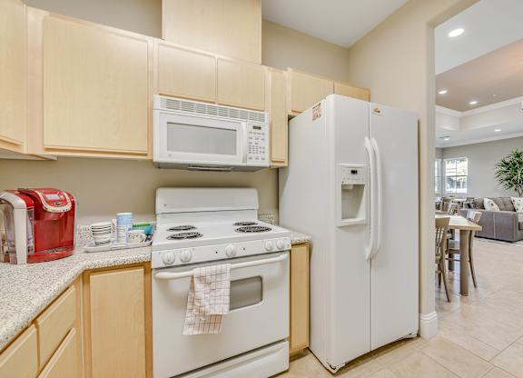 A kitchen with a white refrigerator, white stove, and white microwave.