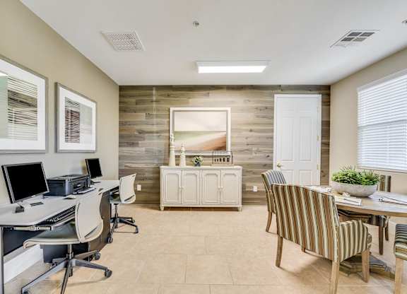 A room with a desk, chairs, and a wooden wall.