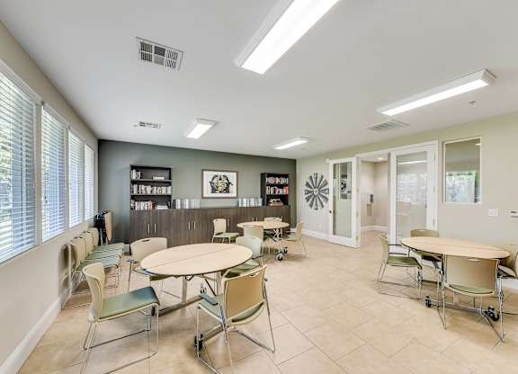 A room with tables and chairs and a bookshelf.