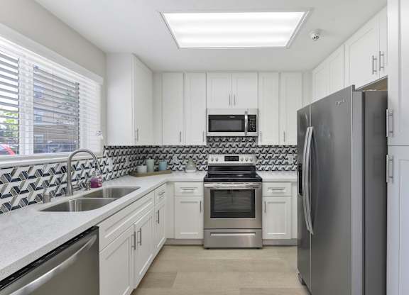 A modern kitchen with white cabinets and stainless steel appliances.