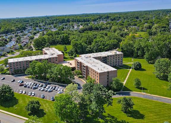 A large building complex with a parking lot in front at Menlo Manor Apartments, Edison, NJ