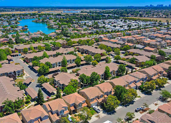 A bird's eye view of a residential area with houses and a lake at Hurley Creek Apartment Homes, Sacramento, California