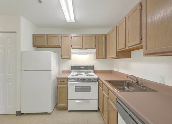 Kitchen with wood cabinets and white appliances at Centennial Court Apartments, Wharton, New Jersey