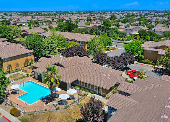 A bird's eye view of a residential area with houses, a swimming pool, and trees. at Hurley Creek Apartment Homes, Sacramento, CA, 95834