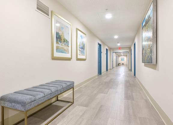 A long hallway with a bench and pictures on the wall.