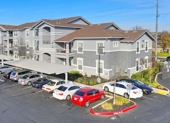 A parking lot in front of a large apartment building.