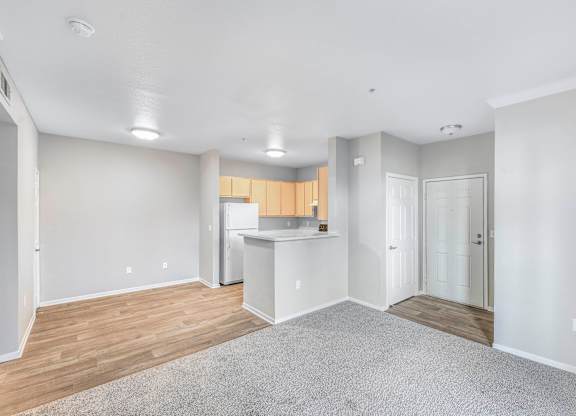A spacious living room with a kitchen in the background.