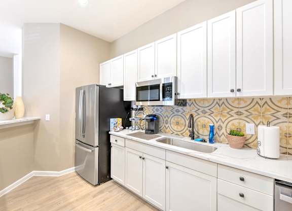 Community kitchen with white cabinets and a stainless steel fridge at Cooper's Crossing, Irving, 75038