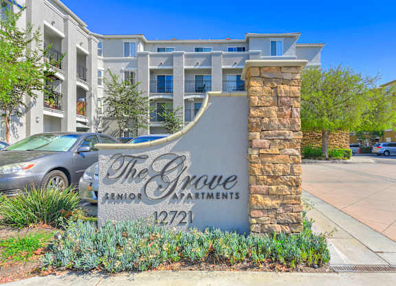 The Grove Senior Apartments is a building with a stone pillar and a sign in front of it.
