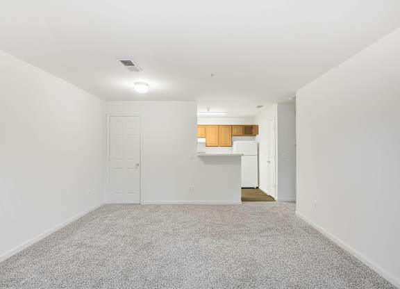 Empty living room with carpet and kitchen view at Acclaim at Ashburn Apartments, Ashburn, VA 20147