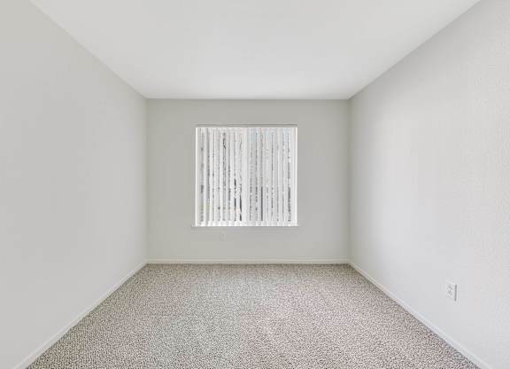 A room with a window covered by vertical blinds.