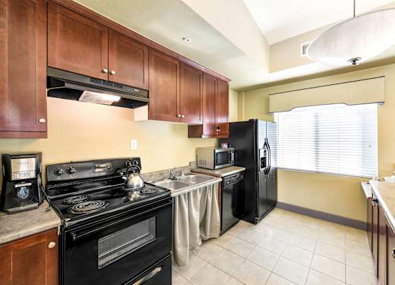A kitchen with a black stove top oven and black refrigerator at Yorba Linda Apartments, Yorba Linda, CA