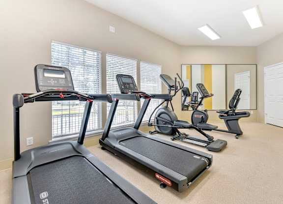 A spacious gym with treadmills, elliptical machines, and other exercise equipment. at Cooper's Crossing, Irving, TX, 75038