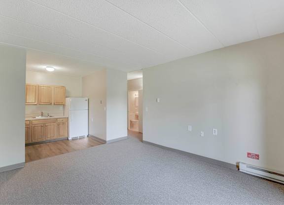 A large empty room with a kitchen area visible through the doorway at Menlo Manor Apartments, Edison, NJ