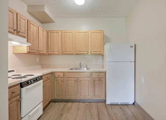 A kitchen with wooden cabinets and a white refrigerator at Menlo Manor Apartments, Edison, NJ, 08820