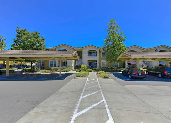A parking lot in front of a building with cars parked at Hurley Creek Apartment Homes, Sacramento, CA