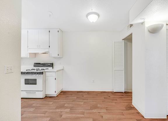 A kitchen with white cabinets and a stove top oven.
