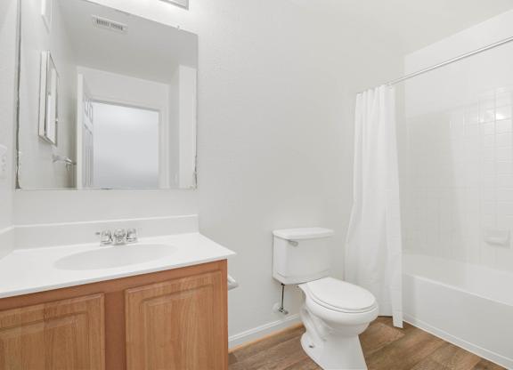 Bathroom with white fixtures and wood flooring at Acclaim at Ashburn Apartments, Ashburn, VA