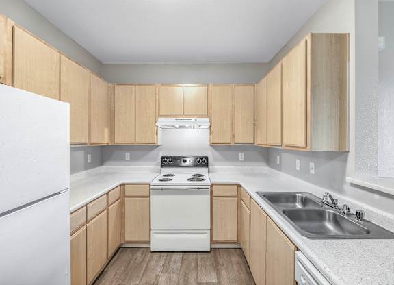 A kitchen with a white fridge, white stove, and wooden cabinets.