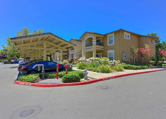 A blue car is parked in a parking lot in front of a building at Hurley Creek Apartment Homes, Sacramento, CA, 95834