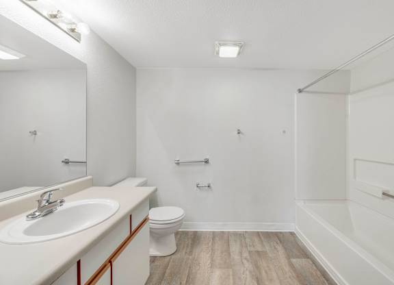 A white bathroom with a sink, toilet, and shower.