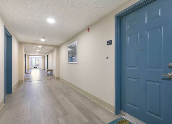 A long hallway with a blue door on the right.