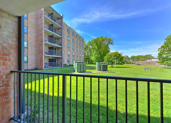 A balcony with a black railing overlooks a grassy area at Menlo Manor Apartments, Edison, New Jersey